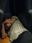 Chris sleeps between seats in the train (Jesenice, Slovenia) resize