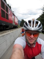 Emily and Cris are passed by a train while riding towards Oberalppass (Switzerland)