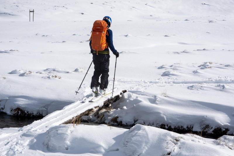 Craig crossing a little bridge (Ski touring Kirtle Burn Hut August 2021)